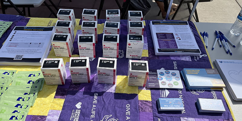 Fentanyl test strips, medication used to rapidly reverse opioid overdose, and information on Denver Health’s hub-and-spoke model of addiction treatment line event display tables.