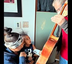 Volunteer playing guitar for pediatric children patients Denver Health