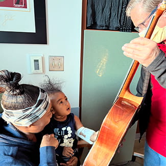 Volunteer playing guitar for pediatric children patients Denver Health