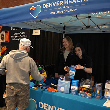 Denver Health Orthopedics representatives speak to a man at the Colfax Marathon expo
