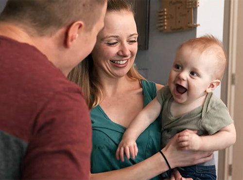 Parents hold baby who is recovering from traumatic brain injury.