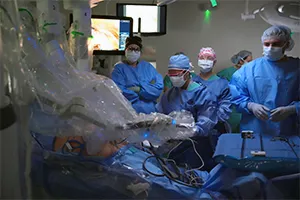 Denver Health medical team surrounds robotic arms in surgery.