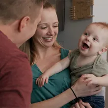 Parents hold baby who is recovering from traumatic brain injury.
