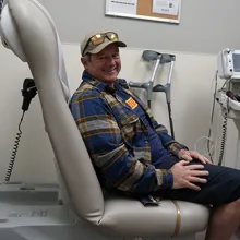 Denver Health patient and Paralympic skier Michael Milton sits in a clinic room waiting for his follow-up appointment.