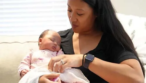 A new mother comforts her newborn baby at home during a visit from Family Connects.