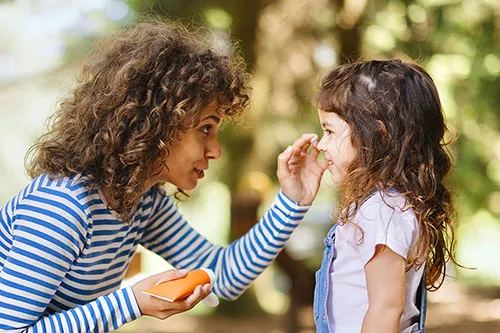 An iStock image of a woman helping a girl apply sunscreen to her face.