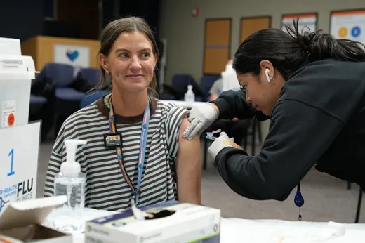 A woman receives a flu shot in her shoulder from a Denver Health nurse.